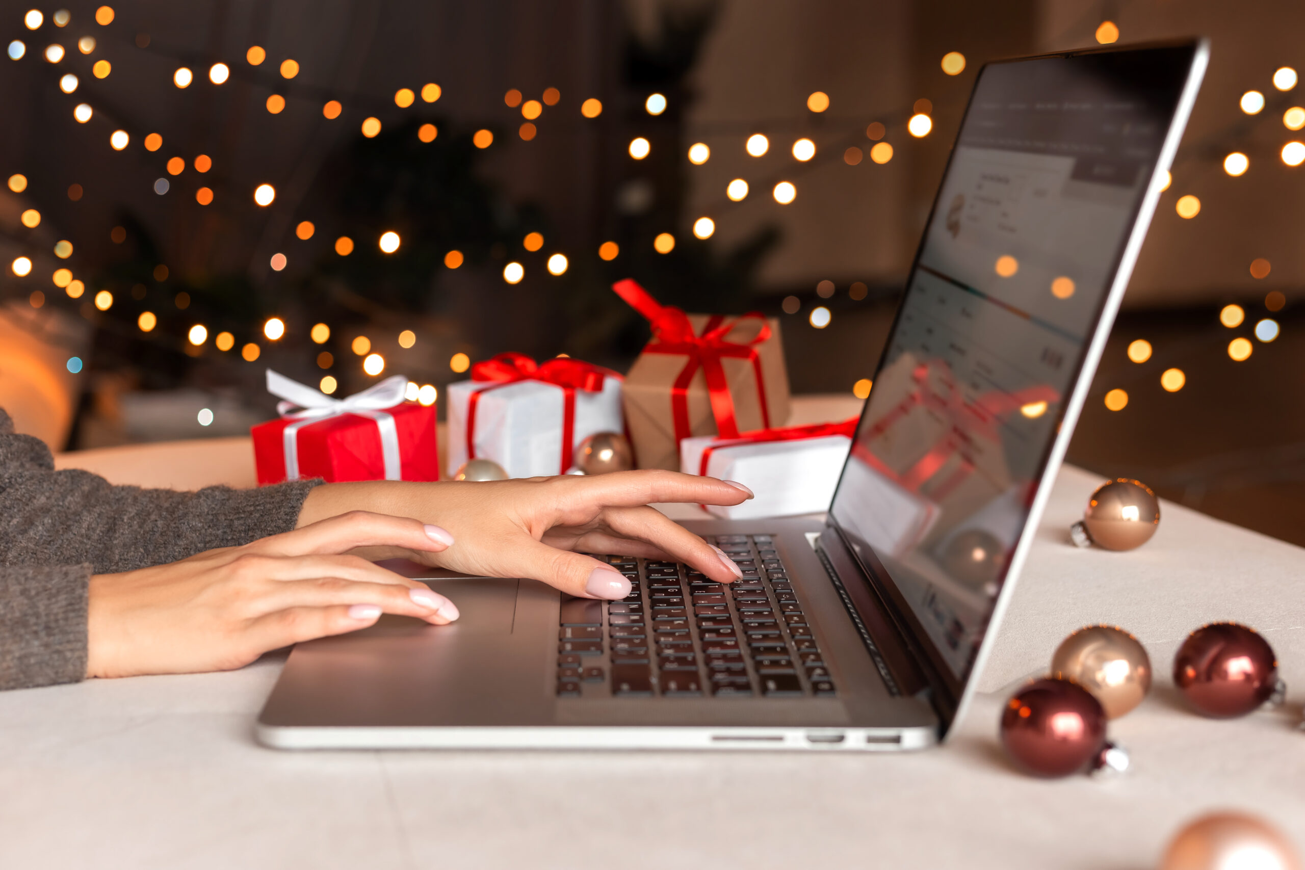 Female,Hands,On,The,Laptop,With,Gifts,And,Blurred,Bokeh